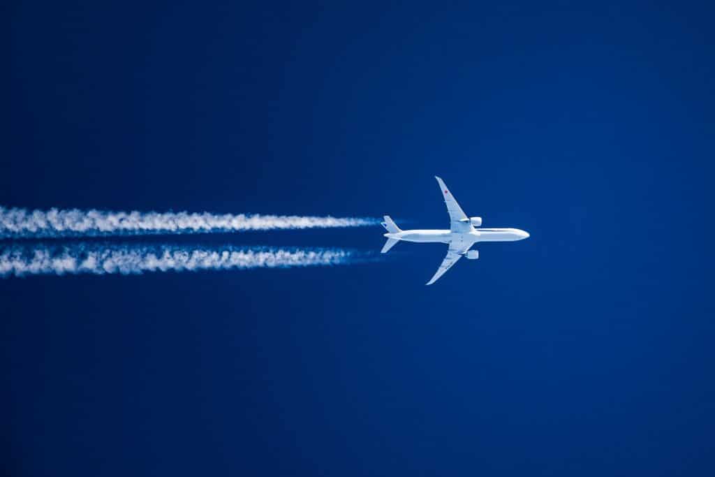 Weißes Flugzeug im blauen Himmel mit Kondensstreifen