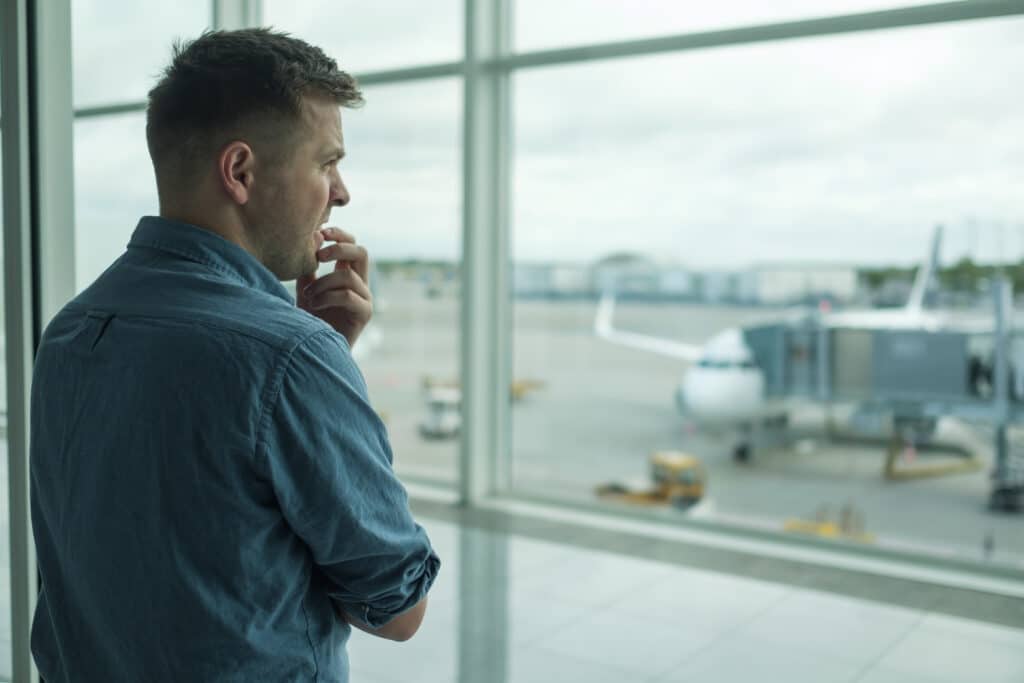 Mann mit Flugangst beobachtet Flugzeuge am Flughafen